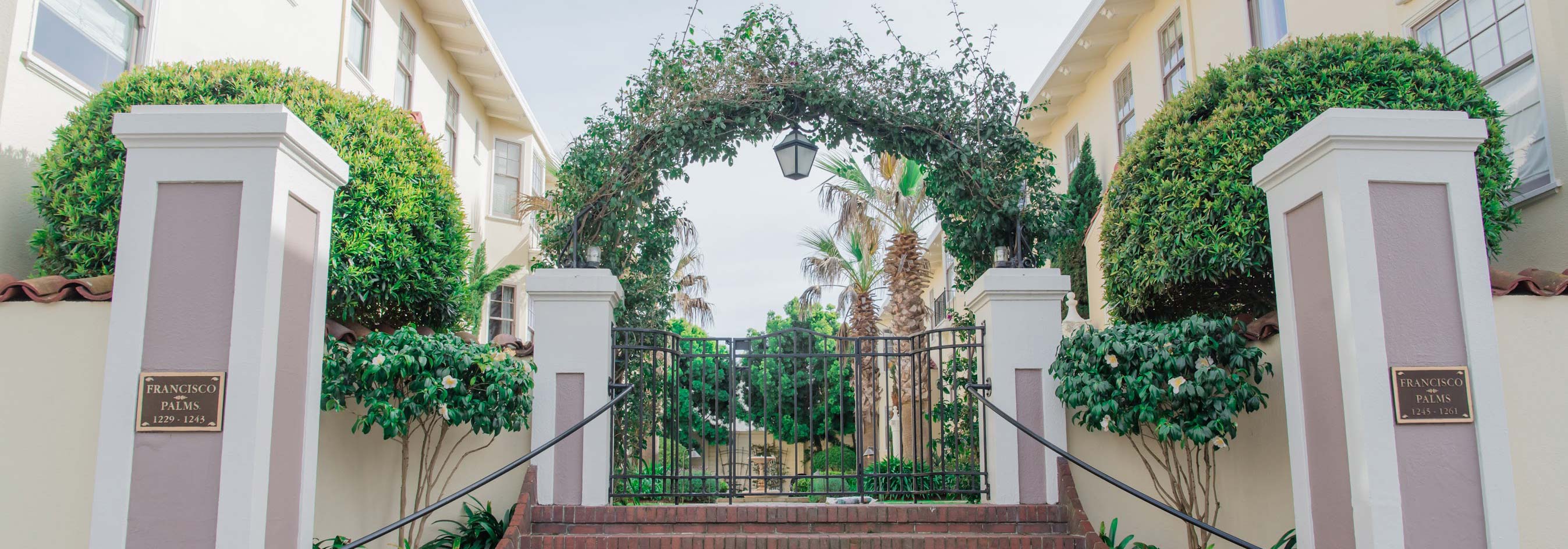 Preventive maintenance for San Francisco apartment building entrance with iron gate and lush greenery